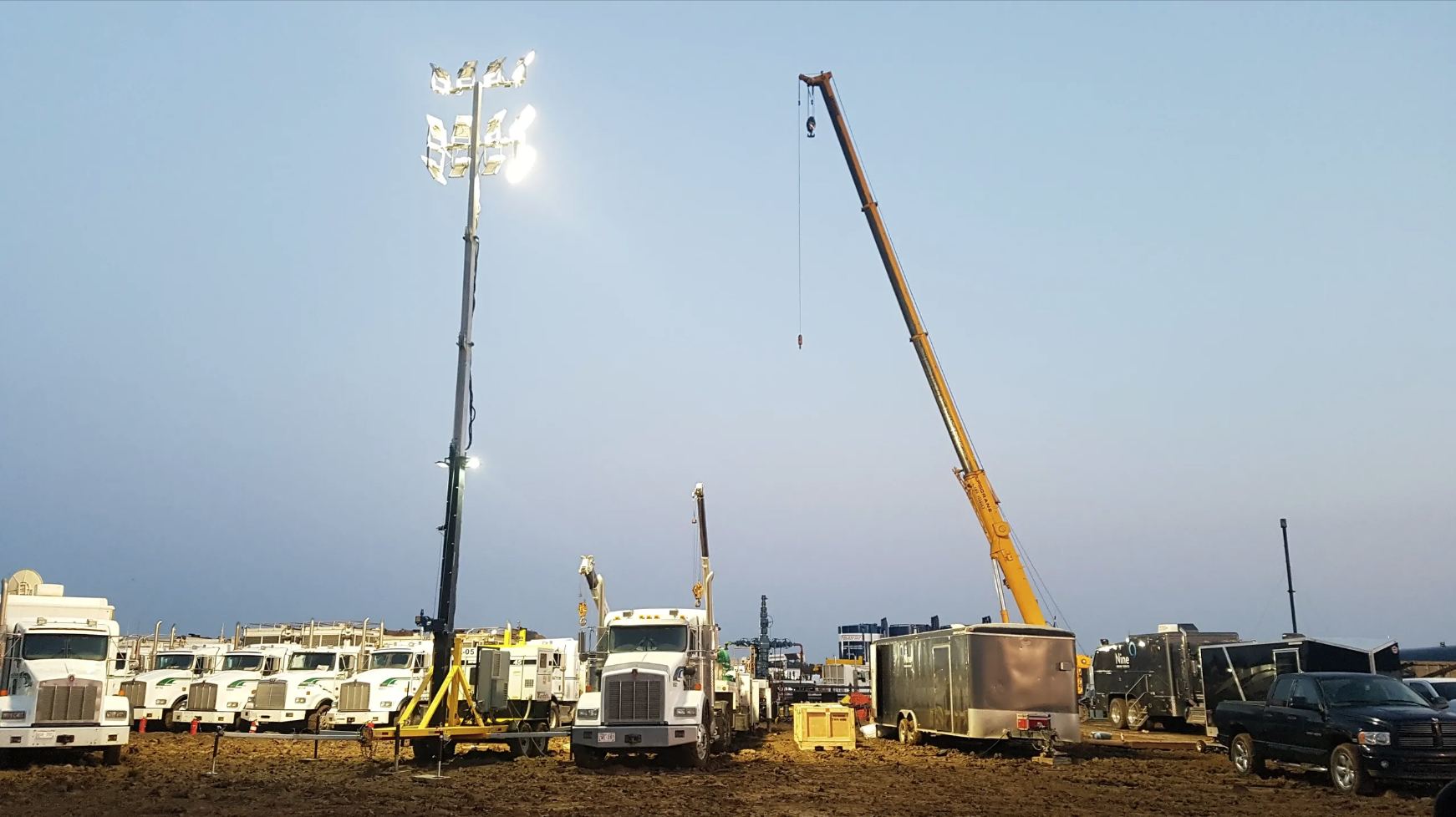 Light tower, crane and several hauling trucks on a worksite Light tower, crane and several hauling trucks on a worksite