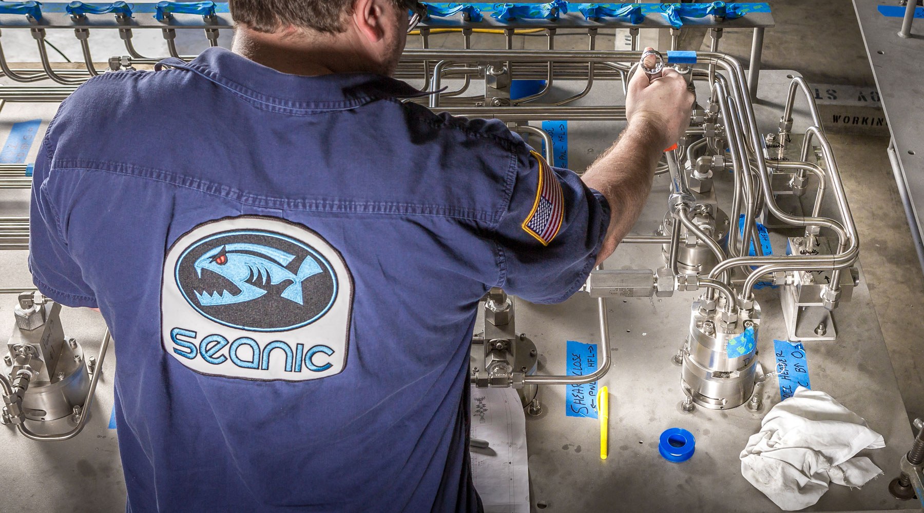 Man wearing Seanic-branded shirt carrying out work on equipment Man wearing Seanic-branded shirt carrying out work on equipment