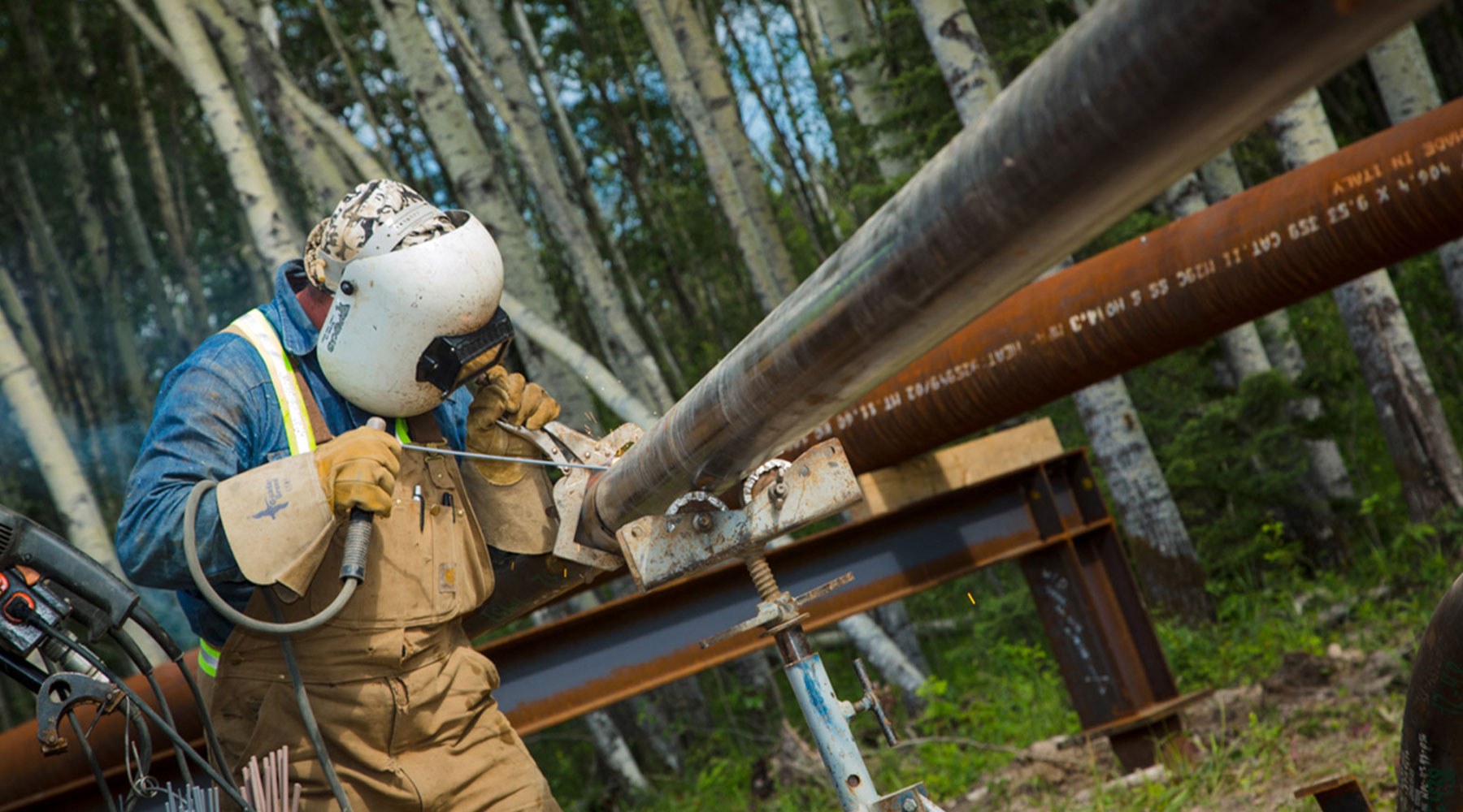 Worker performing maintenance on a pipe in a forest Worker performing maintenance on a pipe in a forest