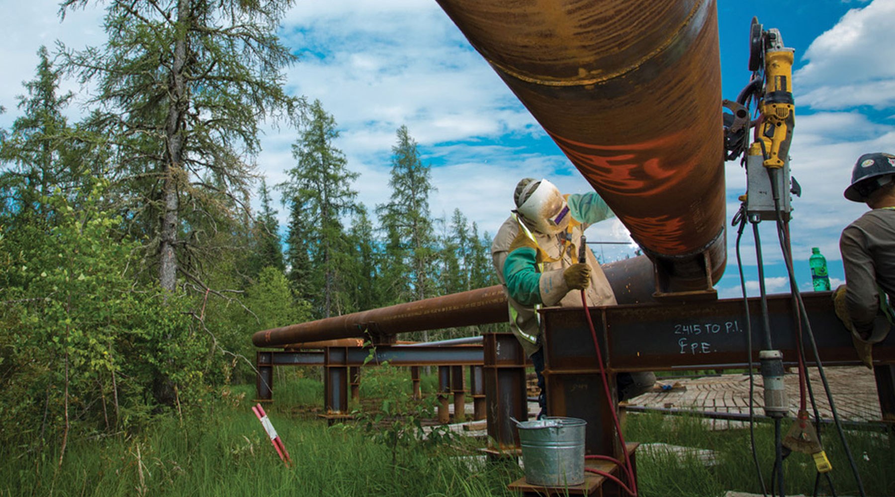 A worker carrying out maintenance on a pipeline in a forest landscape A worker carrying out maintenance on a pipeline in a forest landscape