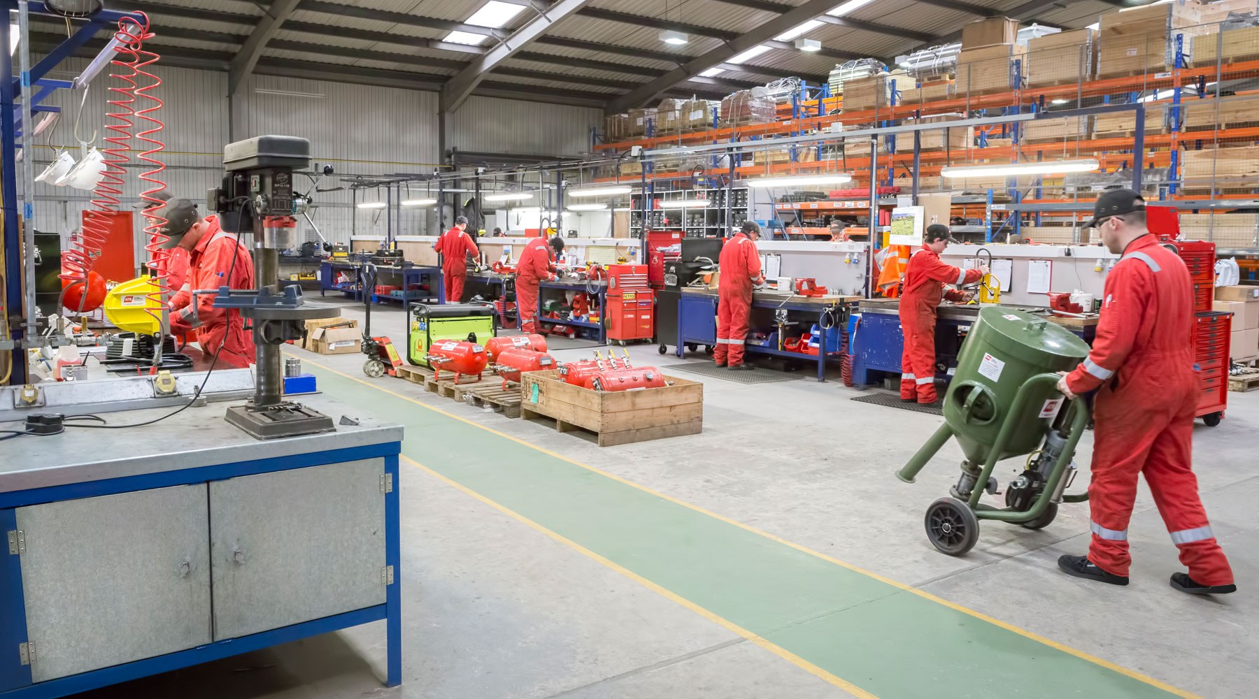 Workers dressed in orange PPE carrying out their duties in a workshop Workers dressed in orange PPE carrying out their duties in a workshop