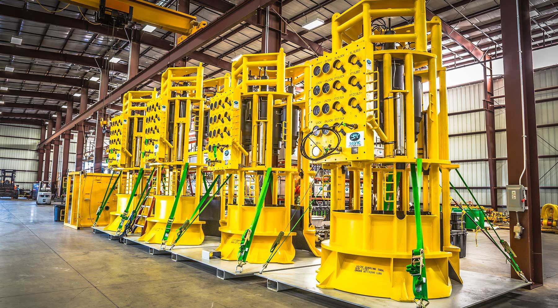 Image of three large pieces of yellow equipment lined up inside a storage facility