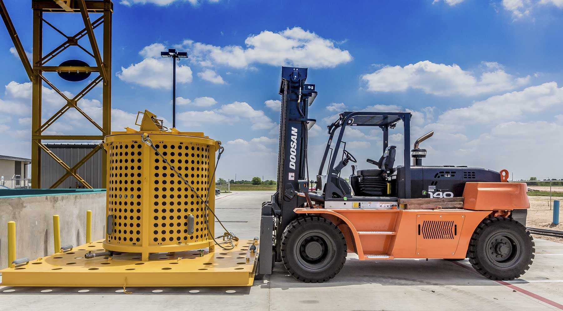 Image of yellow piece of equipment being loaded by an orange forklift