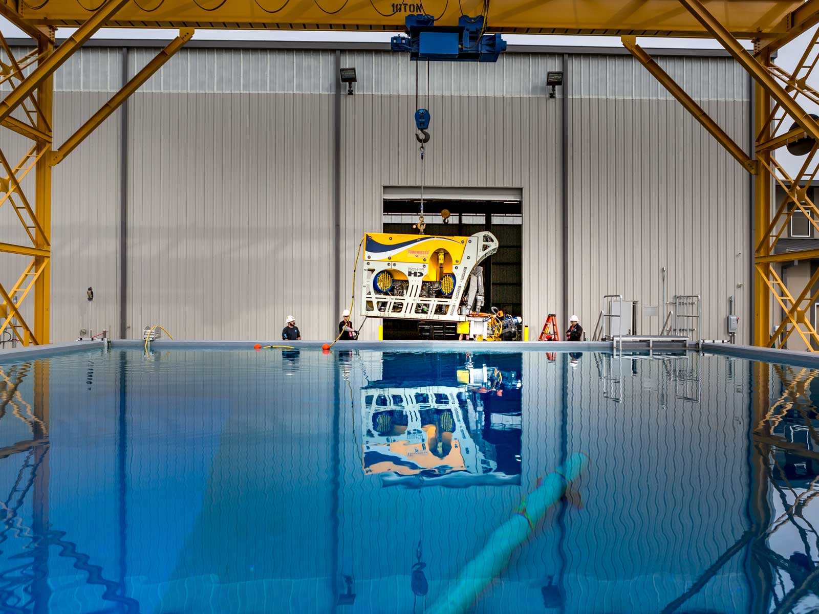 Image of a piece of yellow and white equipment being lowered into a large tank of water